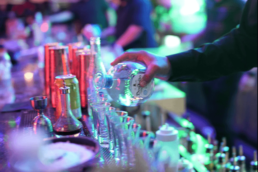 Bartender pouring craft cocktails with vibrant neon lighting